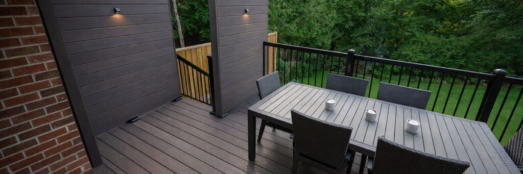 Composite deck with privacy screens, outdoor dining area, and aluminum railings built for a Toronto backyard