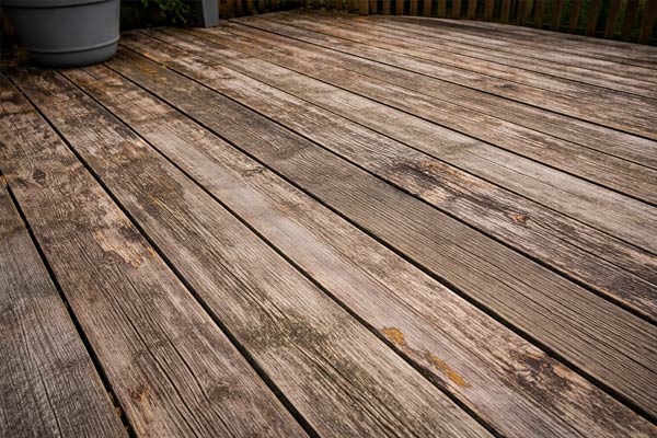 Weathered wood deck boards showing fading cracking and signs of required maintenance