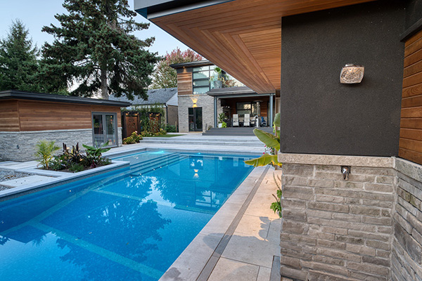 Modern Mississauga backyard landscaping with custom concrete pool, porcelain patio and covered PVC deck